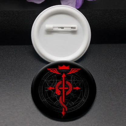 Black circular enamel pin featuring a red winged emblem with a crown inspired by roy mustang fullmetal alchemist
