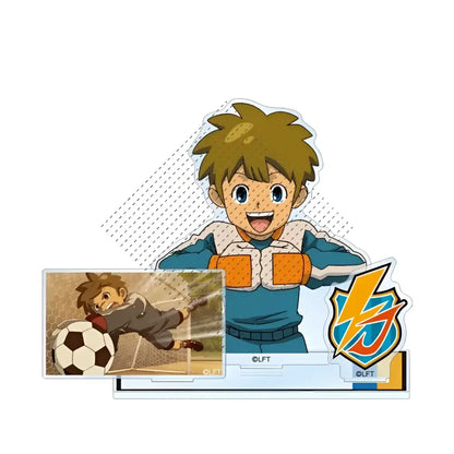 Clear acrylic stand featuring a smiling cartoon boy in blue and orange soccer gear diving for a ball from game inazuma eleven 11