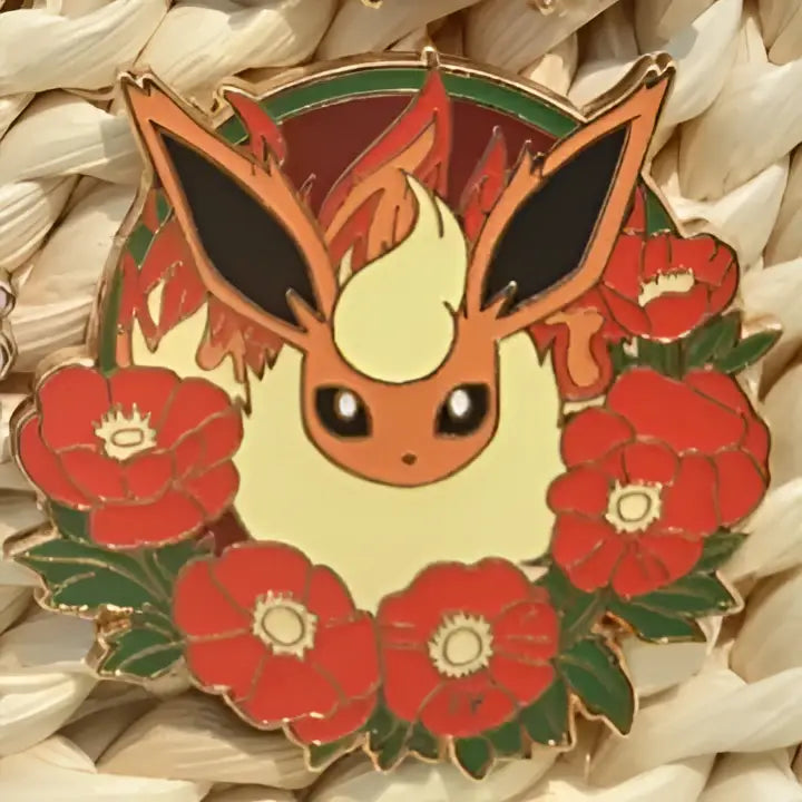 A circular enamel pin featuring a cream eevee with fiery orange markings surrounded by red poppies in gengar anime elf style