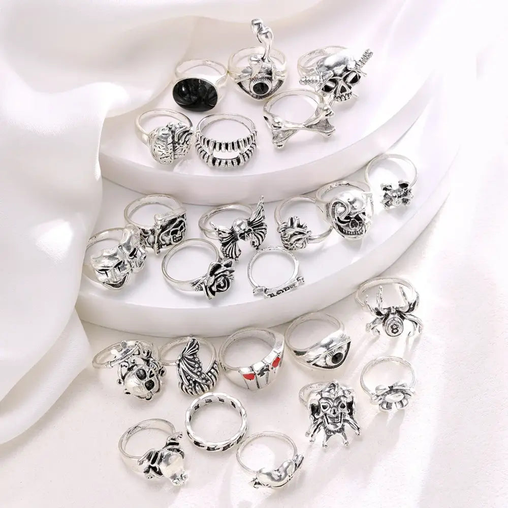 A silver-toned gothic skeleton ring set of 24pcs featuring intricate skulls bats spiders and punk designs