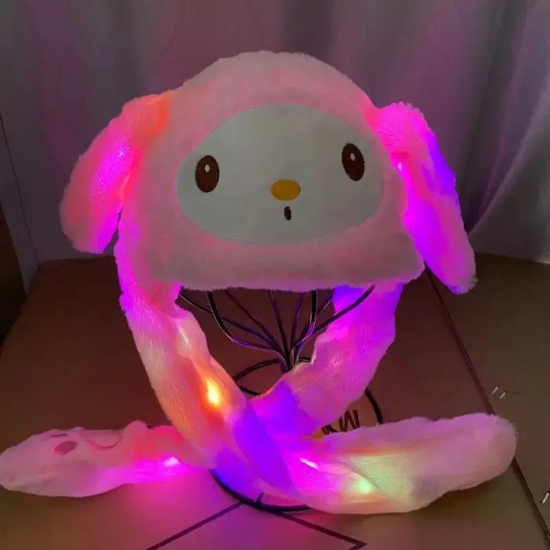 Hello kitty plush winter hat with plush pink and white fabric and led-lit floppy ears and glowing purple orange tail
