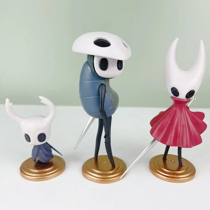 Three hollow knight pvc anime figure set with white helmets black eye sockets horns in blue and red outfits on gold bases