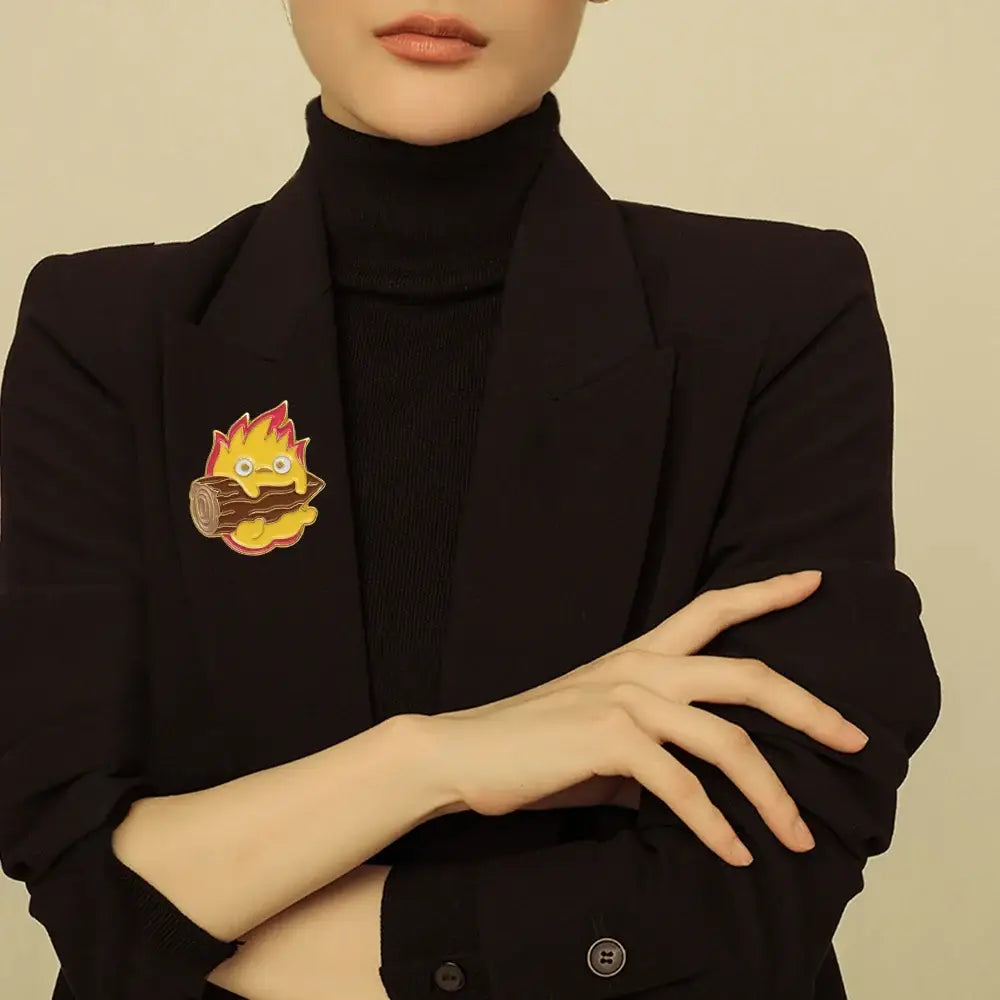 A charming yellow and red flame-themed moving castle calcifer enamel pin featuring a cute cartoonish log with googly eyes
