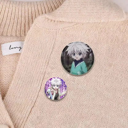 Two circular hunter x hunter killua brooch pin badges with white-haired figure on beige knitted sweater close-up