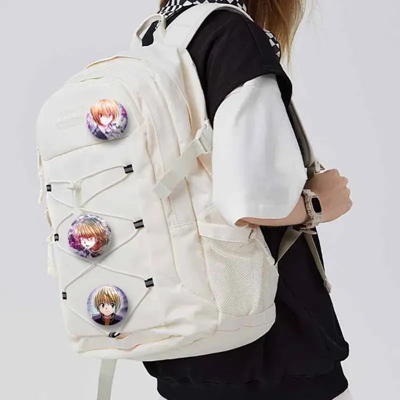 Cream-colored canvas backpack with three hunter x hunter kurapika round brooch pins attached to the front