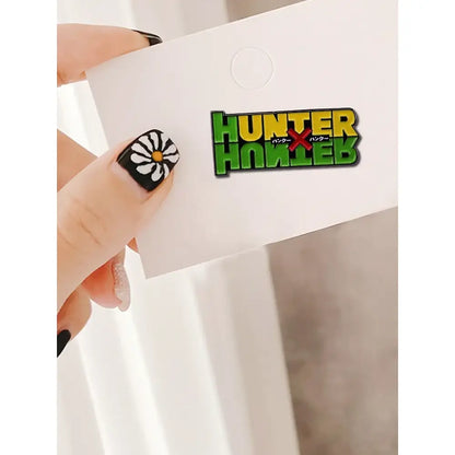 Green and yellow hunter x hunter enamel pin with black japanese text beneath hunter logo brooch fantasy adventure badge