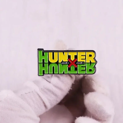 A vibrant green and yellow hunter x hunter logo brooch enamel pin with black outlining and red japanese text fantasy adventure badge