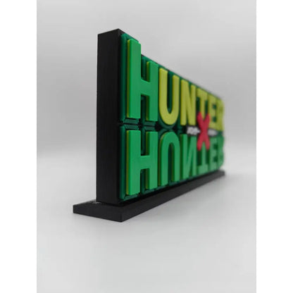 Green and yellow 3d-printed hunter x hunter logo stand with red x on black base for display and decoration