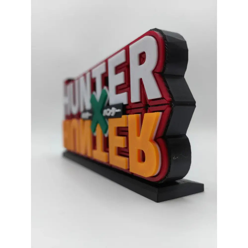 Hunter x hunter logo stand featuring a vibrant 3d-printed design with bold white red orange letters and a green x on black base