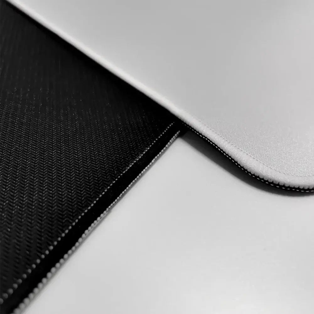Black and silver laptop sleeve with textured fabric and stitched edges shown with hunter x hunter mouse pad rubber base