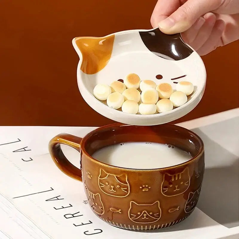 Cute ceramic cat-shaped small dish with white base brown and orange accents holding round biscuits for japanese cat mug set