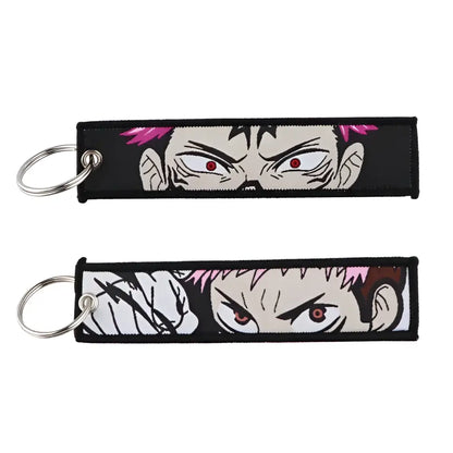 Black embroidered jujutsu kaisen gojo satoru keychain with pink hair and red eyes shown in two variations bag charm