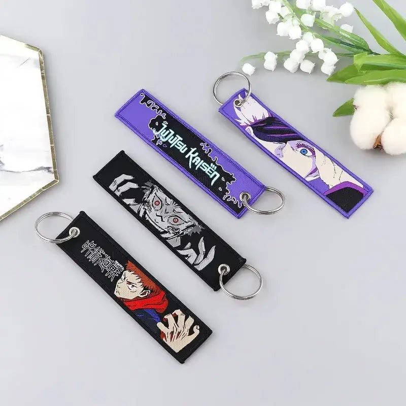 Three embroidered jujutsu kaisen gojo satoru keychains with purple and black fabric bands and metal rings bag charm