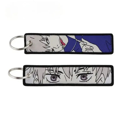 Two embroidered jujutsu kaisen gojo satoru keychains with blue white face and close-up eyes on light gray background