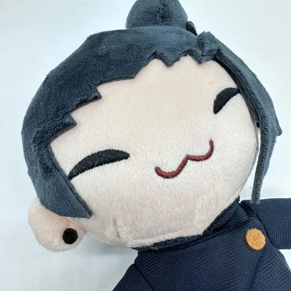 A plush doll of geto suguru from jujutsu kaisen with dark gray hair navy blue outfit and orange button in soft cosplay style