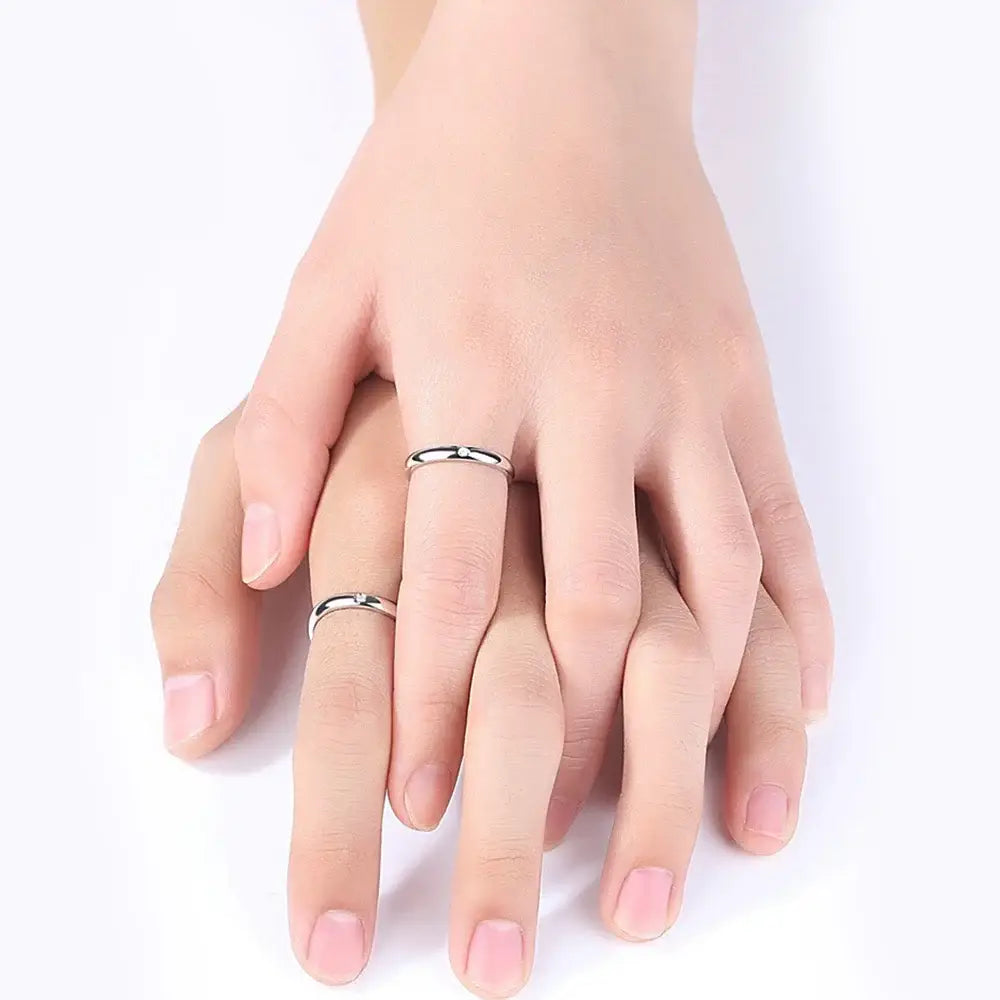 A pair of minimalist silver jujutsu kaisen yuta okkotsu cosplay rings with smooth bands worn on intertwined fingers