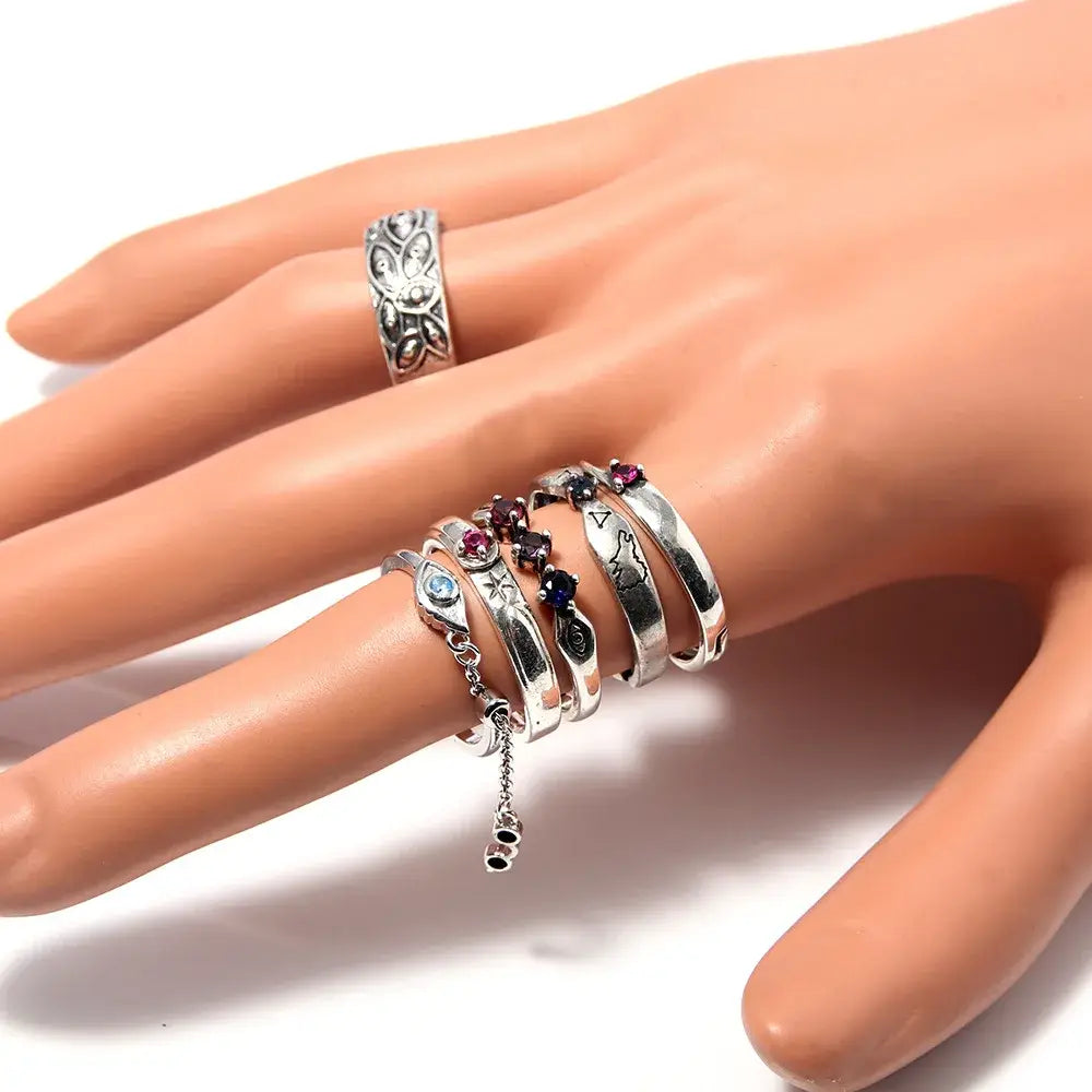 A stack of silver jujutsu kaisen yuta okkotsu couple rings with intricate designs and purple blue black gemstones