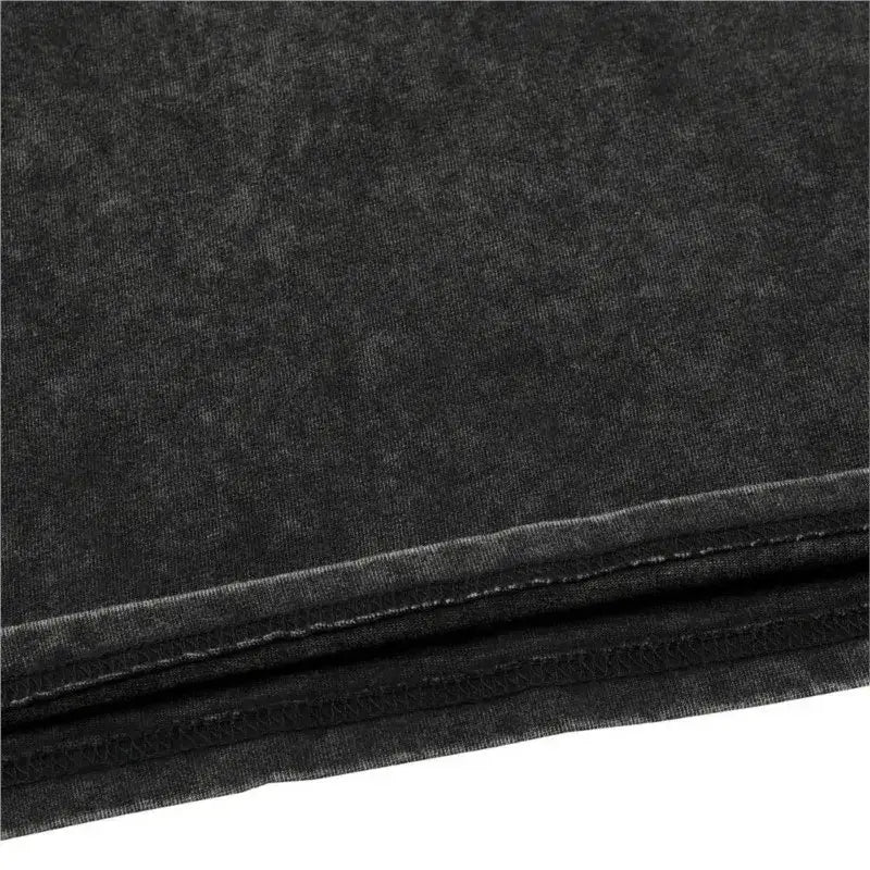 Black denim fabric with faded textured finish and visible stitching on hem of kaiju no 8 washed cotton t shirt for men