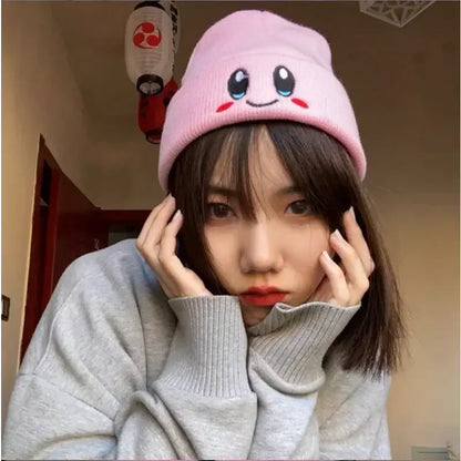 Pink knit kirby plush hat featuring kawaii blue eyes and red cheeks embroidered on a soft plush hat