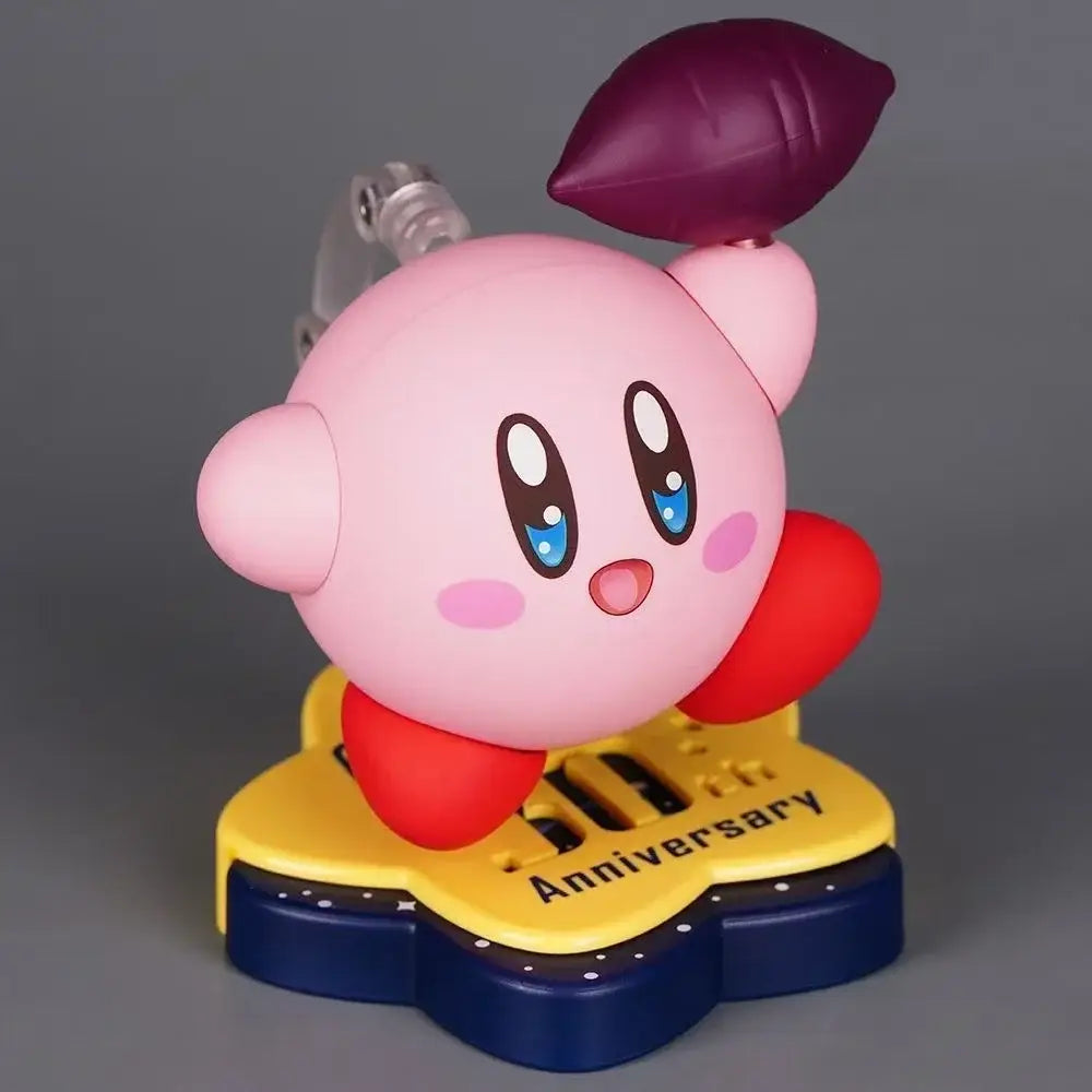 Pink kirby pvc figure with red arms and a purple leaf on head standing on yellow and blue 30th anniversary edition base