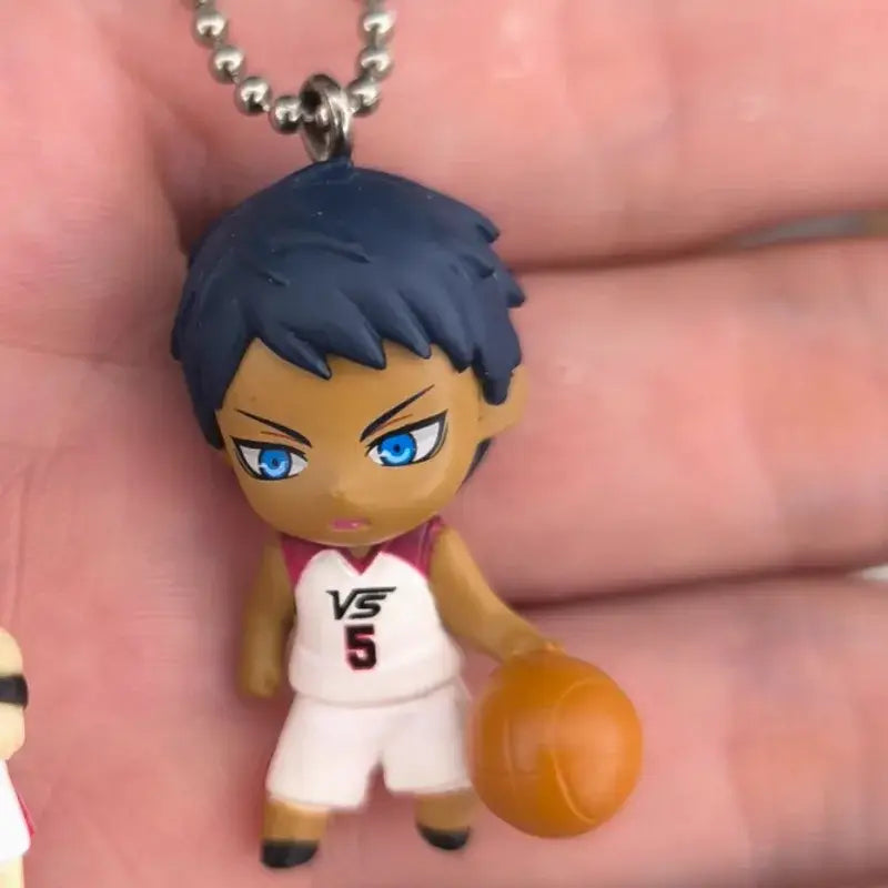 A chibi-style kuroko’s basketball kise ryota pvc keychain with dark blue hair bright blue eyes white vs 5 jersey holding orange ball