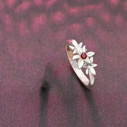 Delicate silver necklace pendant featuring three white flower motifs with a central red gemstone for cosplay accessory