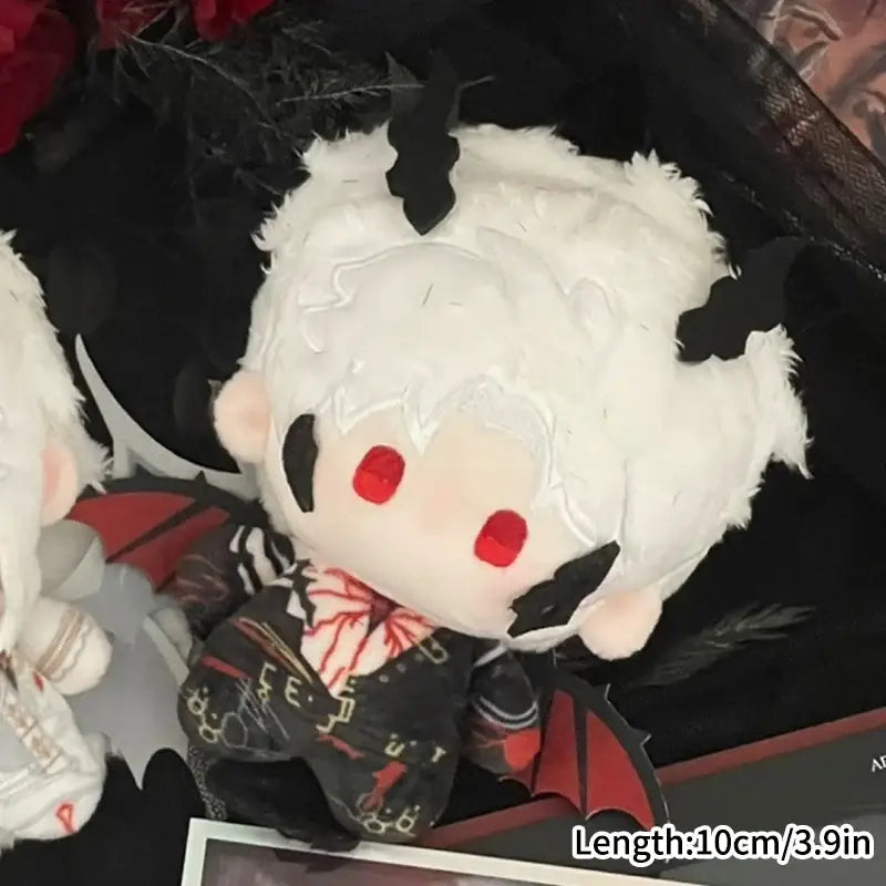 A cute cartoon plush vampire bag charm with white fluffy hair red eyes black bat wings and dark patterned outfit