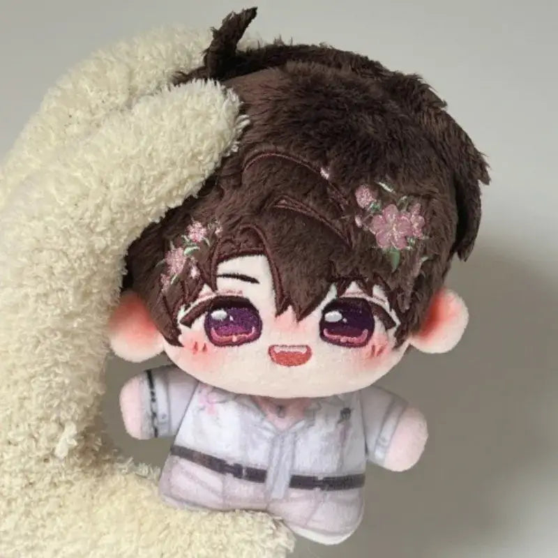 A plush love and deepspace keychain with brown fluffy hair pink flowers purple eyes wearing a white outfit cute cartoon bag charm