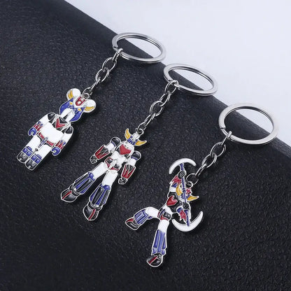 Three metallic keychains with colorful enamel-coated robot figures featuring the mazinger z bombardier logo design