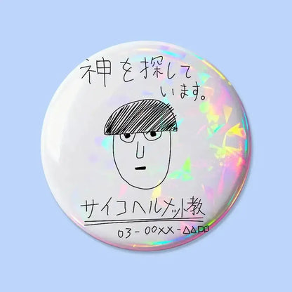 Mob psycho pin badge round iridescent button with black sketch of face wearing glasses and hat over japanese text