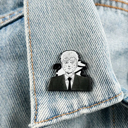 Black and white enamel mob psycho lapel pin of reigen arataka in a suit with question marks pinned to denim fabric