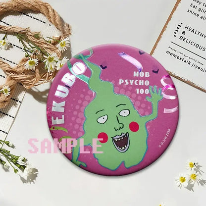 A vibrant pink round kageyama button pin featuring a green cartoon character from mob psycho 100 on a glossy surface