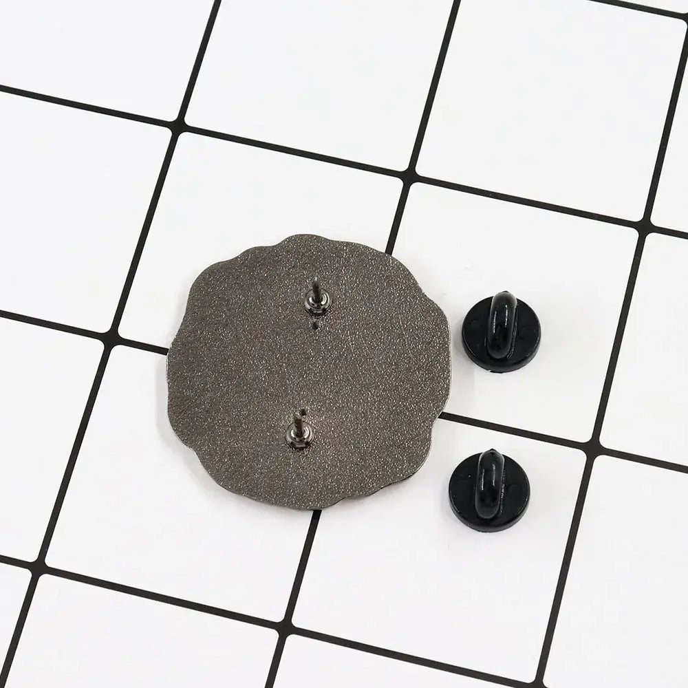 Back view of a dark gray scalloped-edge metal floating badge with textured surface and silver kageyama lapel pin fasteners