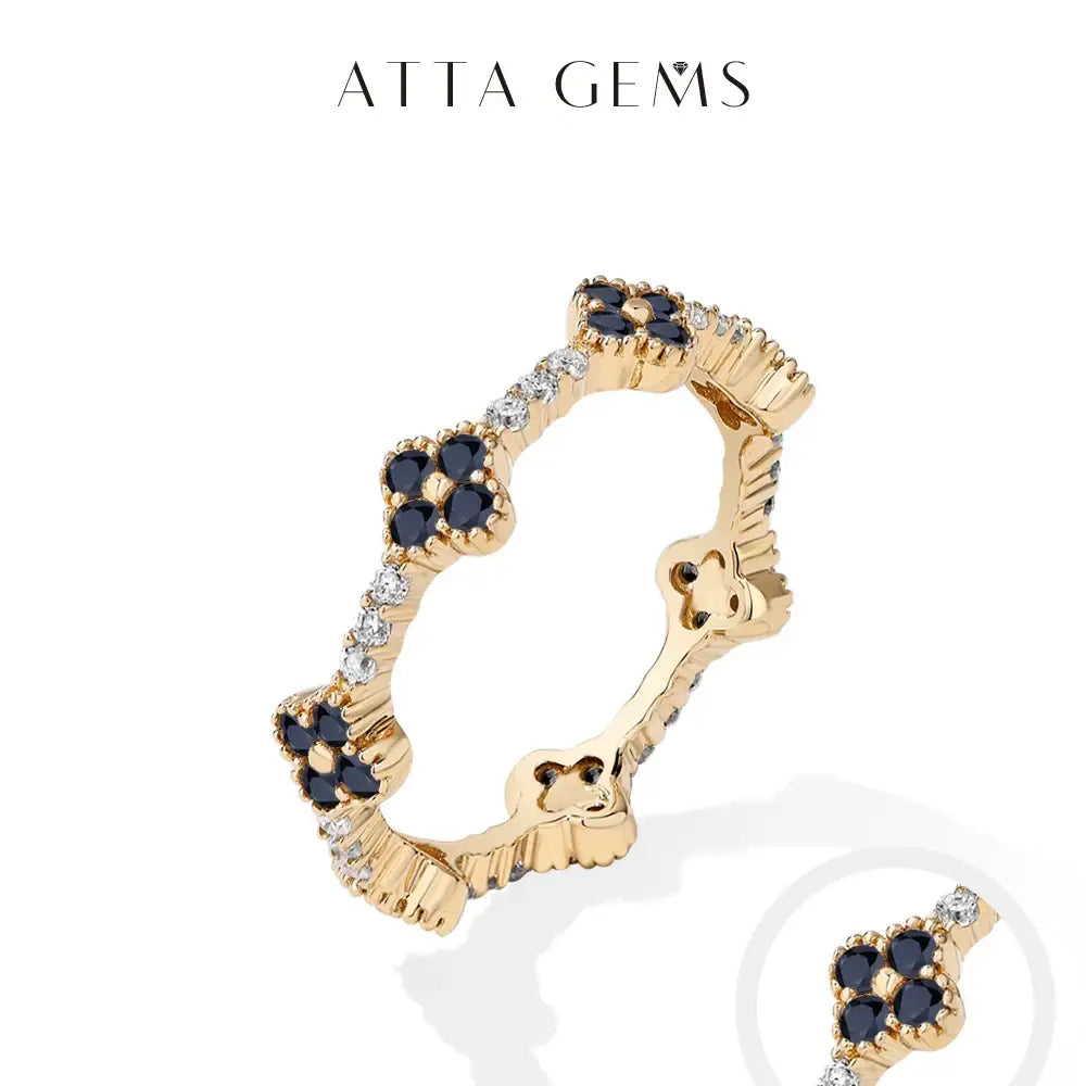 Gold-toned moissanite eternity ring in sterling silver with floral designs featuring dark blue sapphires and clear diamonds