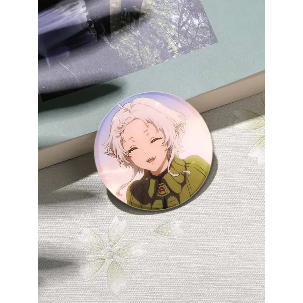 A circular glossy handmade tinplate pin badge featuring roxy migurdia with silver hair and a green jacket