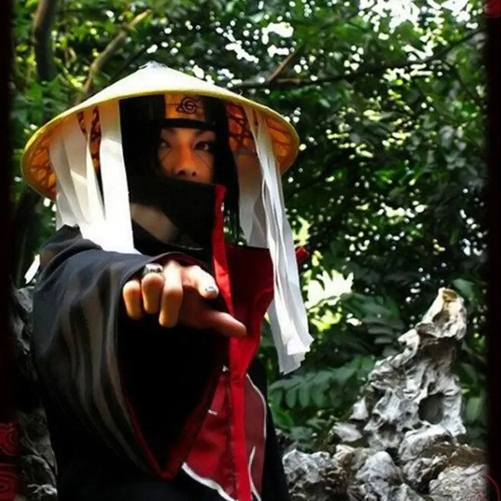A person wearing a yellow conical hat with white ribbons and orange headband paired with a dark red akatsuki cosplay cloak set