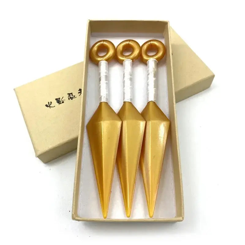 Three golden kunai model knives with white handles made of pvc neatly arranged in a beige box for display