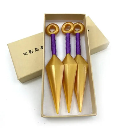 Three golden kunai model knives with purple handles and gold rings in a beige box made of durable pvc