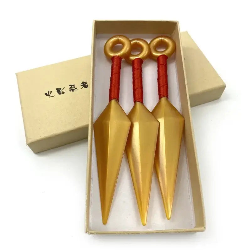 Three golden kunai model knives with red handles made of durable pvc neatly arranged in a beige gift box