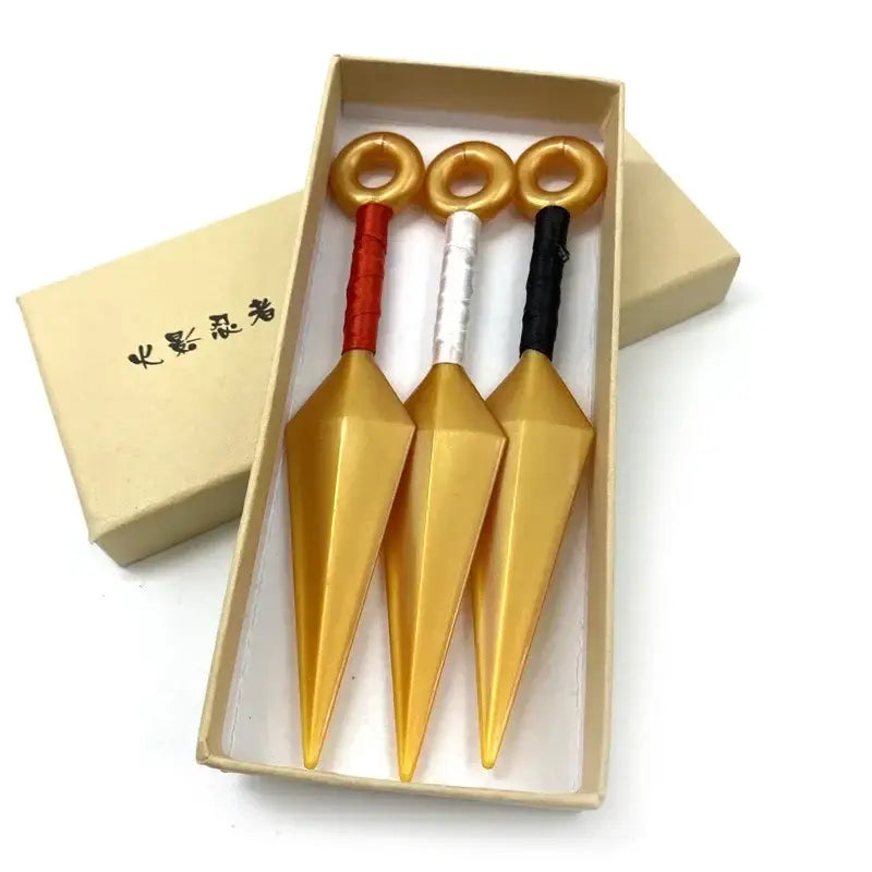Three golden kunai model knives with red white and black handles in a beige gift box made of pvc material