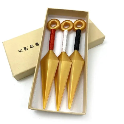 Three golden kunai model knives with red white and black handles in a beige gift box made of pvc material