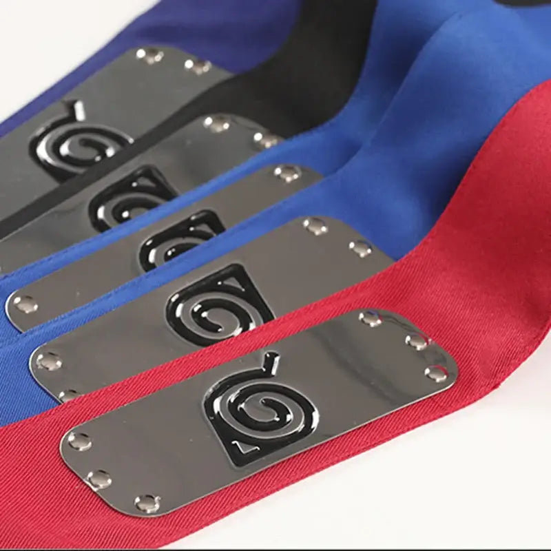 Silver metal forehead protector plates with black embossed spiral logos on blue and red fabric headbands for ninjas