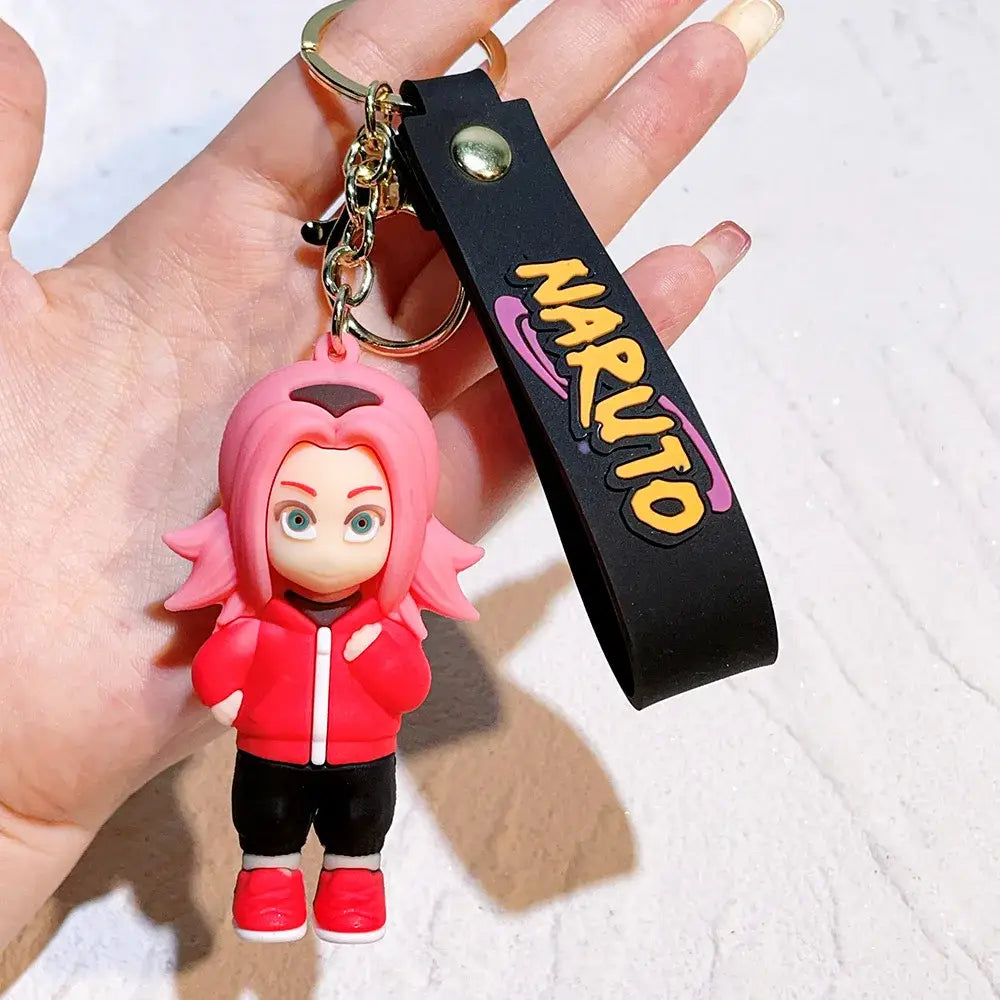 Pink-haired sakura naruto pvc silicone keychain in red jacket and black pants with black wrist strap featuring yellow naruto lettering