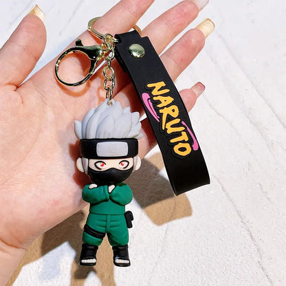 A green and black naruto pvc silicone keychain with white spiky hair red eyes a headband and crossed arms