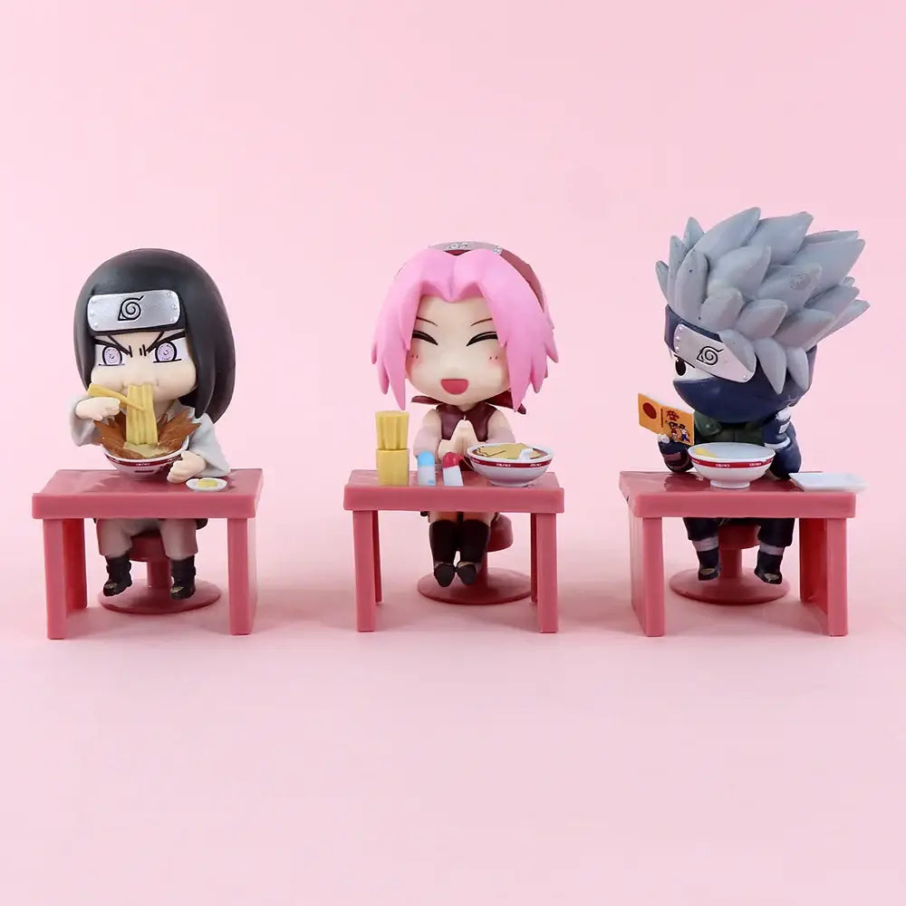 Three chibi-style naruto anime figurines seated at pink plastic tables in naruto and sasuke blind box figure set desktop display