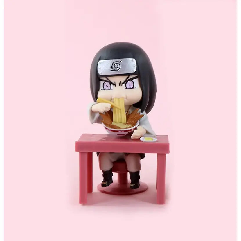 Chibi-style black-haired naruto figure with silver headband seated at pink table eating noodles from bowl in blind box set