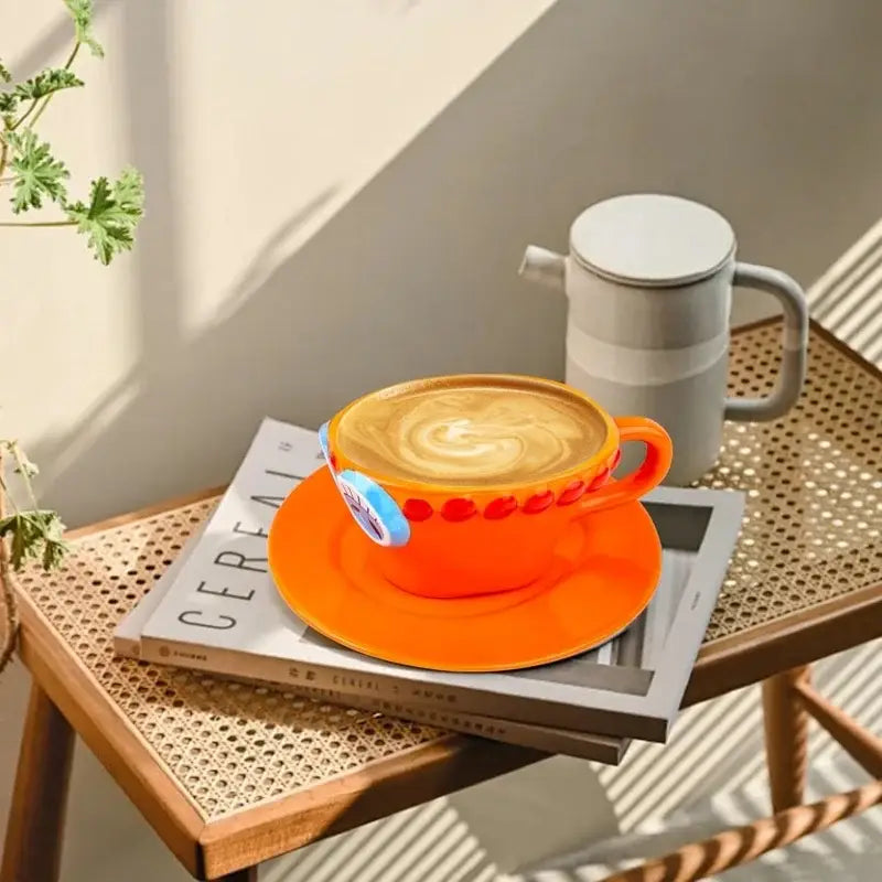 Vibrant orange ceramic cup and saucer set with red dotted rim and blue one piece chopper hat-shaped sticker