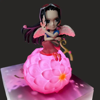 One piece devil fruit night light figure with pink glowing flower base and chibi character in blue top and red skirt seated on it