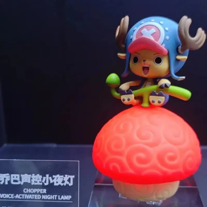 A vibrant red one piece devil fruit night light with chopper figurine blue hat and green staff voice controlled led