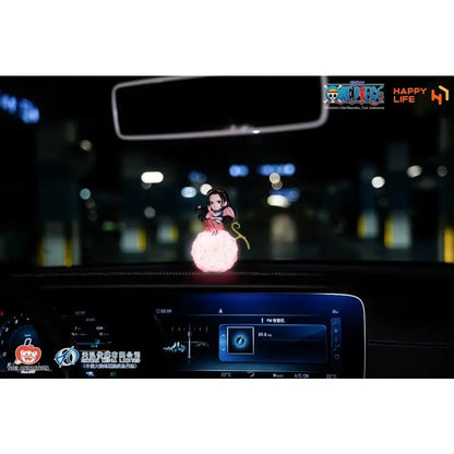 A glowing pink and black piece devil fruit night light anime figurine with a voice-controlled led fluffy base on car dashboard